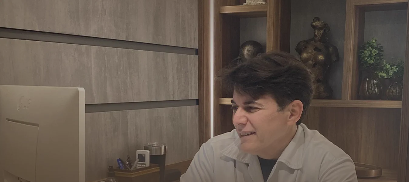 Dr. Carlos Eduardo Slaibi Conti, de jaleco branco, em seu consultório
